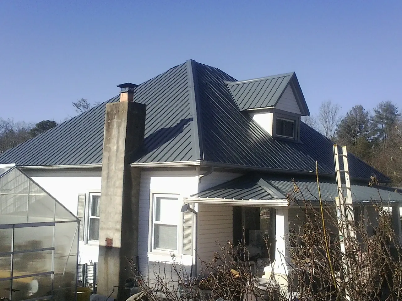 Dark blue standing seam metal roof on a white farmhouse with dormer — Slate & Tile Roof Repair by Roofing Brothers in Suisun City