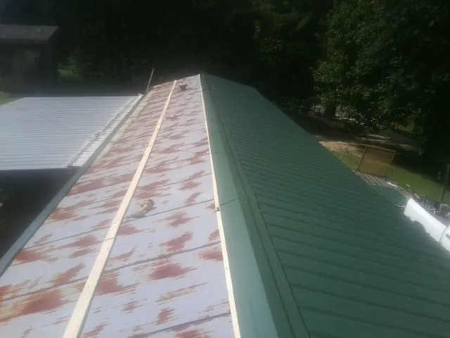 Old rusted panels beside newly installed green metal roofing — Wind Damage Roof Repair by Roofing Brothers in Suisun City