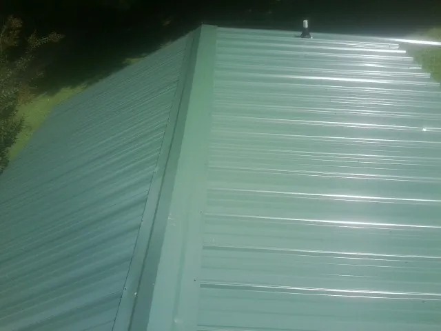 New green metal panels meeting at the ridge of a roof — Flat Roof Repair work by our crew in Suisun City