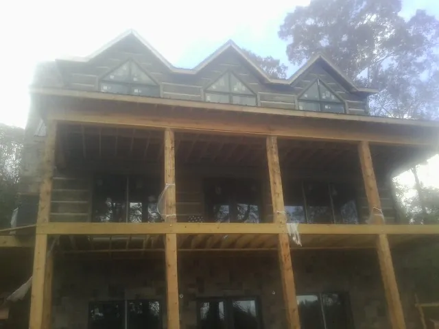 Dormers and porch framing on a large log home under construction — Roof Coating work by our crew in Suisun City