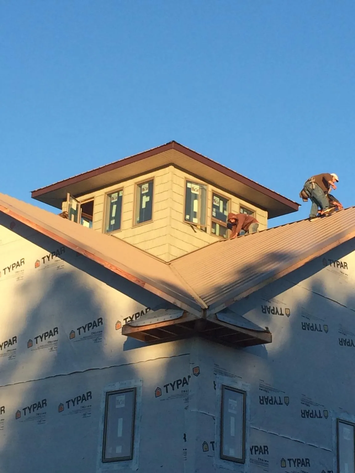 Roofers working around a rooftop cupola on a new metal roof at sunset — Roof Waterproofing in Suisun City by Roofing Brothers